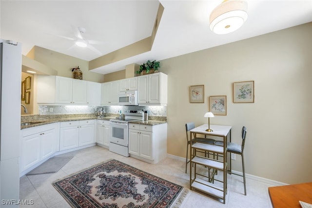 kitchen with white appliances, a sink, tasteful backsplash, light stone counters, and ceiling fan