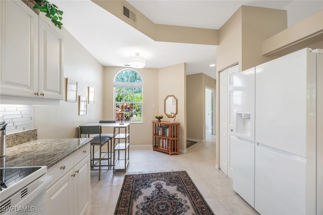 kitchen featuring white appliances, white cabinets, light stone counters, light tile patterned floors, and backsplash