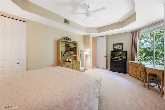 bedroom featuring light carpet, a ceiling fan, and a raised ceiling
