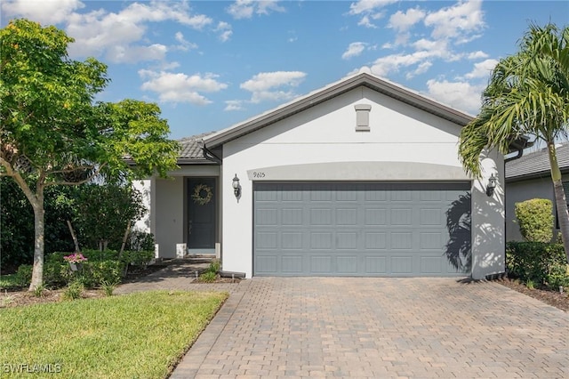 ranch-style house with stucco siding, an attached garage, and decorative driveway