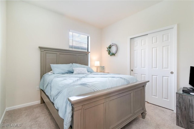 bedroom featuring baseboards, a closet, and light colored carpet