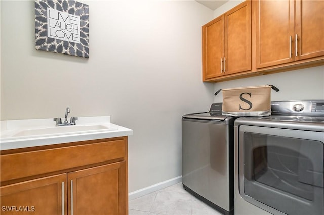 clothes washing area with a sink, light tile patterned floors, washing machine and dryer, and cabinet space