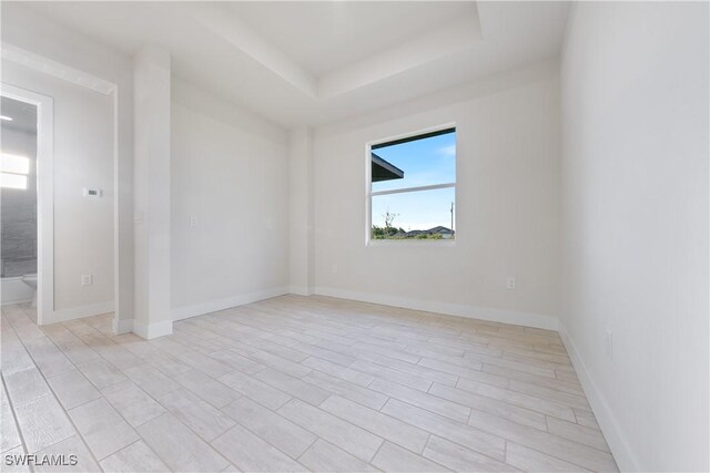 spare room featuring baseboards and a tray ceiling