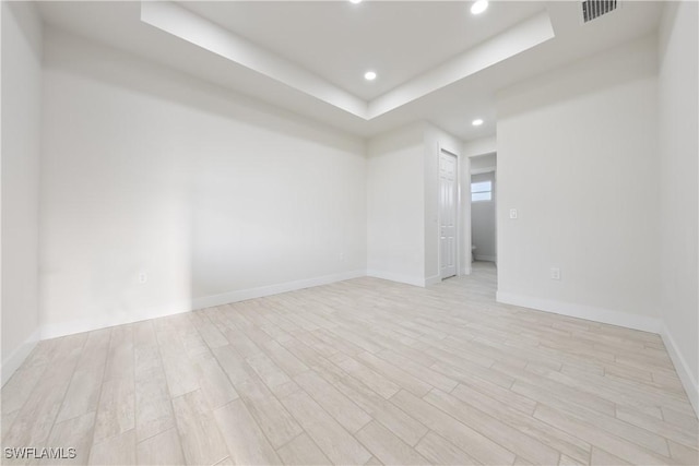 spare room featuring recessed lighting, a raised ceiling, visible vents, light wood-type flooring, and baseboards