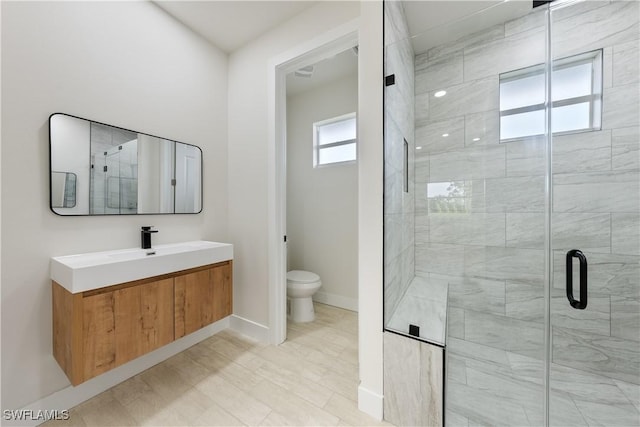 bathroom featuring baseboards, toilet, vanity, and a stall shower