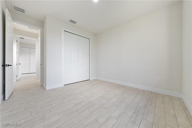 unfurnished bedroom featuring baseboards, light wood finished floors, and visible vents