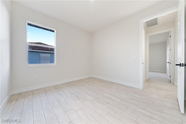 empty room featuring baseboards, visible vents, and light wood-style floors