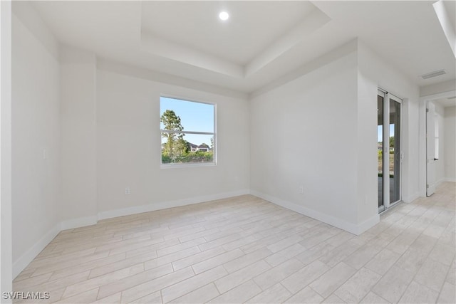 spare room with recessed lighting, baseboards, visible vents, and a raised ceiling