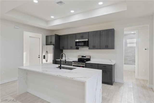 kitchen featuring stainless steel appliances, a tray ceiling, visible vents, a sink, and baseboards