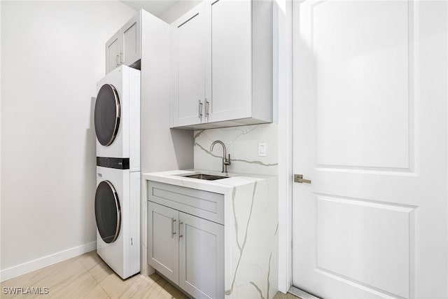 1990 47th Ave NE, Naples, FL 34120 - clothes washing area with cabinet space, stacked washing maching and dryer, baseboards, and a sink
