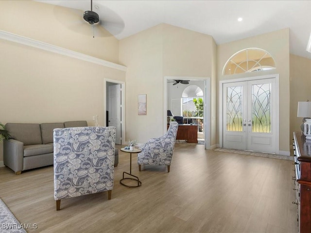 foyer entrance featuring a ceiling fan, french doors, high vaulted ceiling, and light wood-style flooring