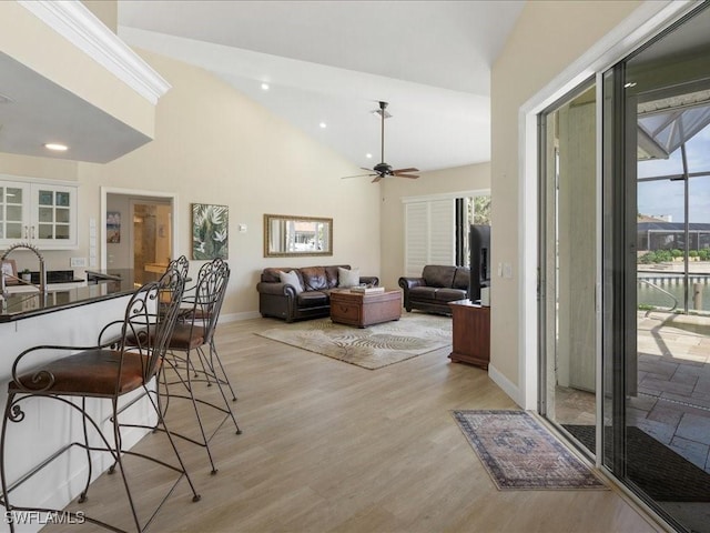 living room with light wood-style flooring, a healthy amount of sunlight, baseboards, and ceiling fan