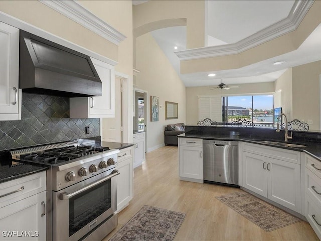 kitchen featuring a sink, decorative backsplash, stainless steel appliances, light wood finished floors, and wall chimney exhaust hood