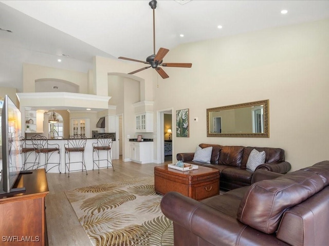 living area featuring ceiling fan, a towering ceiling, light wood-style floors, and recessed lighting