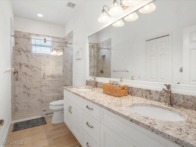 bathroom with toilet, a marble finish shower, a sink, and visible vents