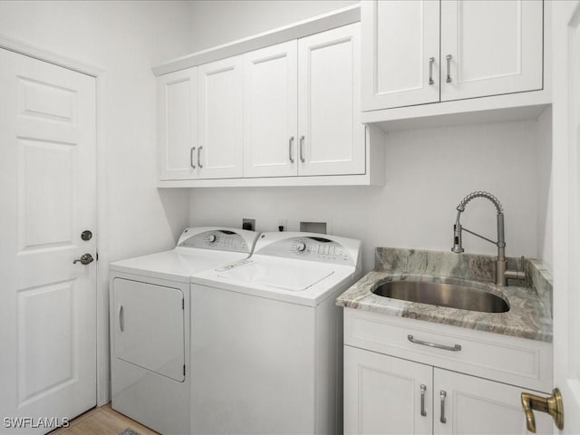 clothes washing area featuring separate washer and dryer, a sink, and cabinet space