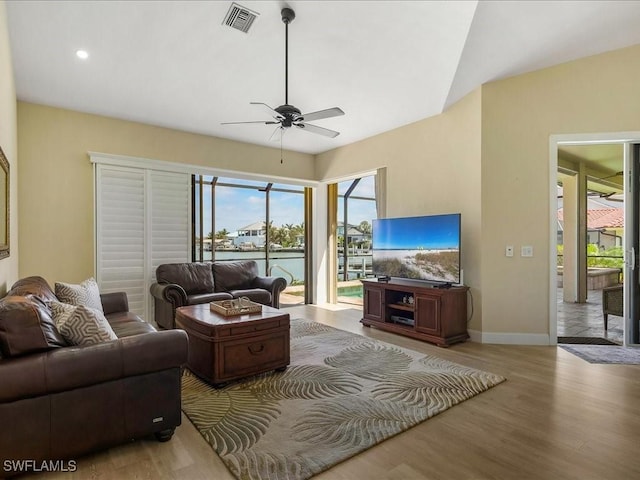 living room with vaulted ceiling, baseboards, visible vents, a ceiling fan, and wood finished floors