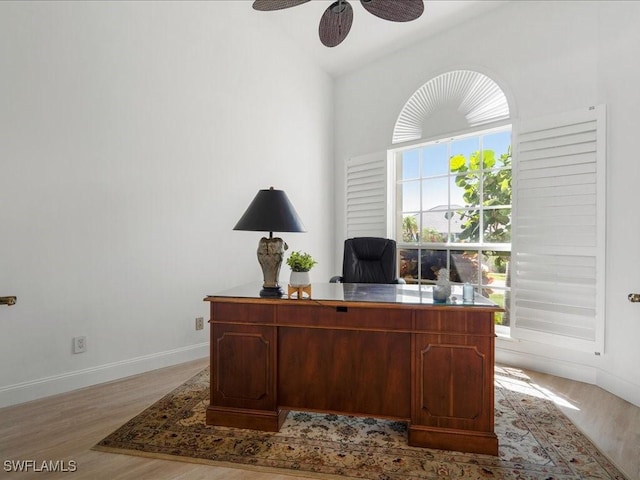 office space featuring ceiling fan, vaulted ceiling, light wood-style floors, and baseboards