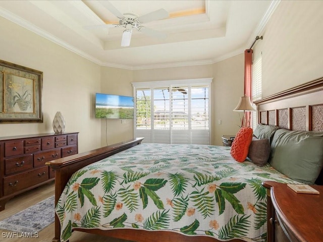bedroom with a tray ceiling, light wood-type flooring, crown molding, and ceiling fan
