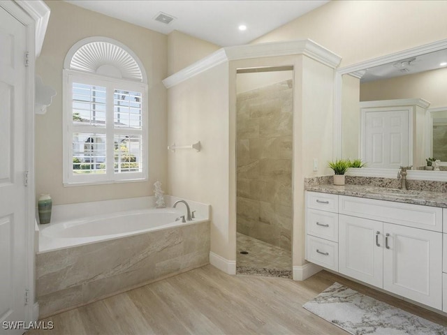 full bath with a garden tub, wood finished floors, vanity, visible vents, and tiled shower