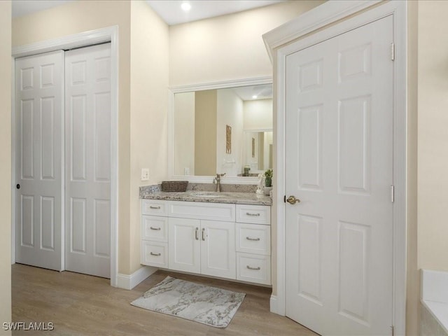 bathroom with baseboards, wood finished floors, and vanity