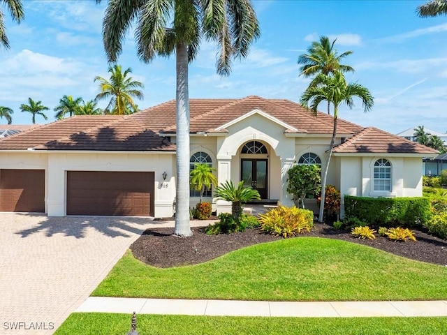 mediterranean / spanish house featuring french doors, an attached garage, stucco siding, and driveway