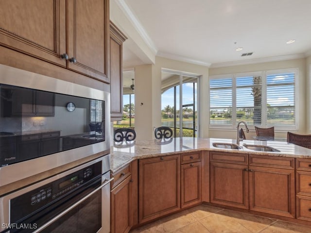 28561 Calabria Ct Unit 102, Naples, FL 34110 - kitchen featuring stainless steel oven, brown cabinets, a sink, built in microwave, and crown molding