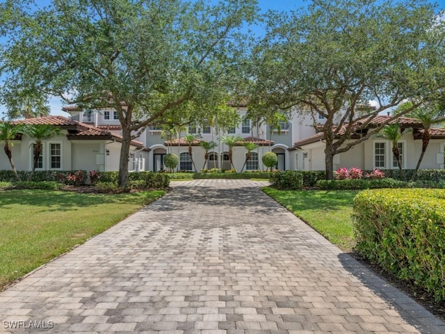28561 Calabria Ct Unit 102, Naples, FL 34110 - view of front of house with decorative driveway, a tiled roof, stucco siding, and a front yard