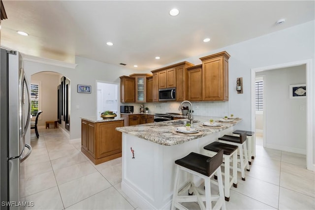 1518 Mcgregor Reserve Dr, Fort Myers, FL 33901 - kitchen with stainless steel appliances, brown cabinetry, arched walkways, a peninsula, and light stone counters
