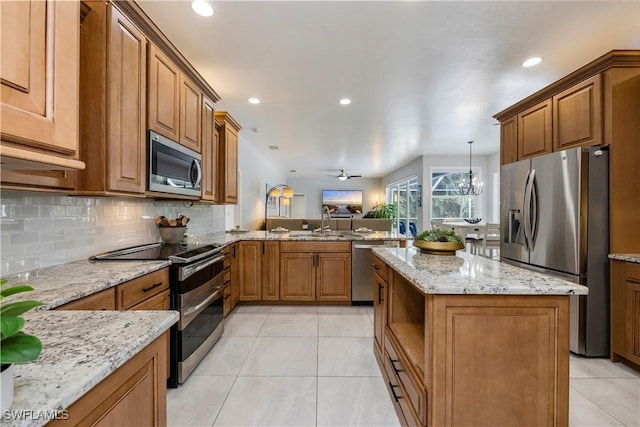1518 Mcgregor Reserve Dr, Fort Myers, FL 33901 - kitchen featuring appliances with stainless steel finishes, light tile patterned flooring, a peninsula, backsplash, and brown cabinets