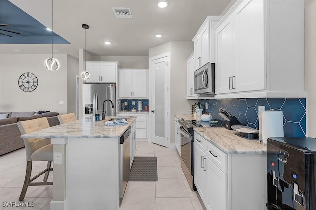 137 SE 23rd Ter, Cape Coral, FL 33990 - kitchen featuring light tile patterned floors, a breakfast bar area, backsplash, appliances with stainless steel finishes, and visible vents