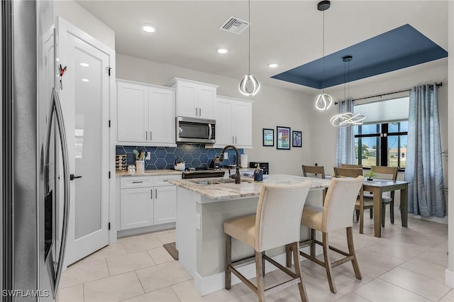 137 SE 23rd Ter, Cape Coral, FL 33990 - kitchen with an island with sink, visible vents, a sink, decorative backsplash, and appliances with stainless steel finishes
