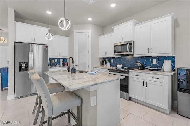 137 SE 23rd Ter, Cape Coral, FL 33990 - kitchen featuring a sink, a center island with sink, decorative backsplash, appliances with stainless steel finishes, and hanging light fixtures