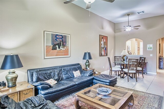 living area featuring light tile patterned floors, arched walkways, a ceiling fan, and visible vents