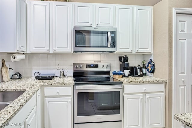kitchen with white cabinetry, backsplash, and appliances with stainless steel finishes