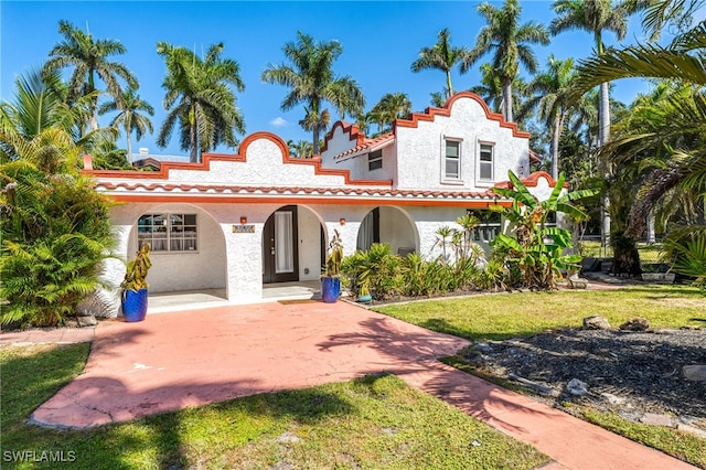 mediterranean / spanish home with stucco siding, a tiled roof, and a front yard