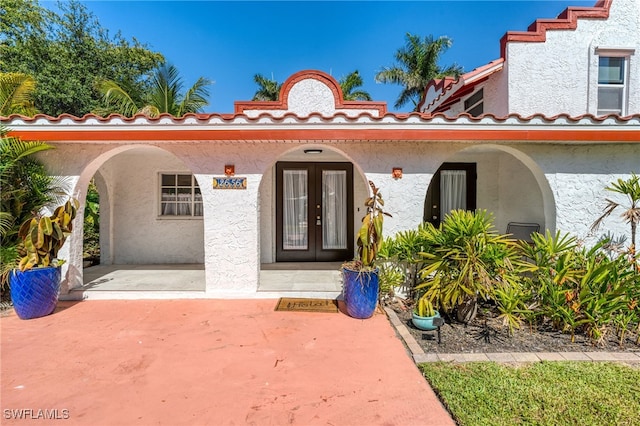 view of exterior entry with a porch and stucco siding