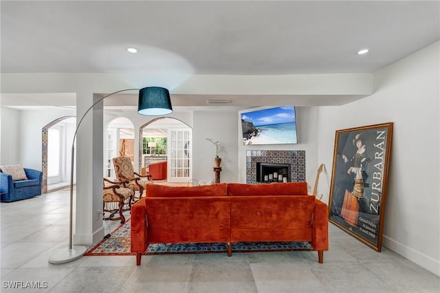 living room featuring visible vents, arched walkways, a tile fireplace, baseboards, and recessed lighting