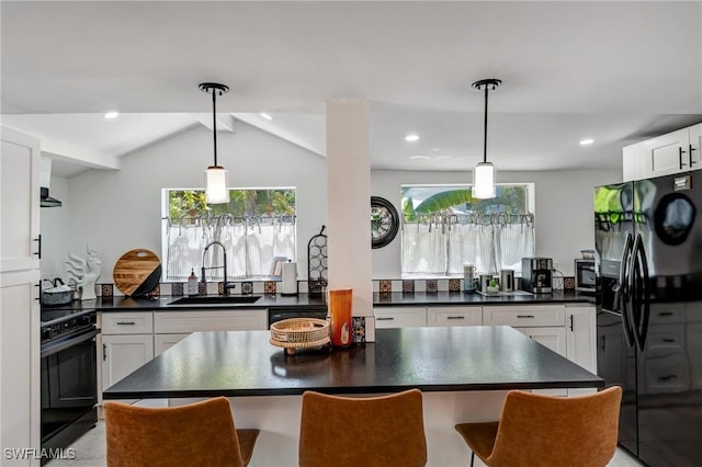kitchen featuring white cabinetry, dark countertops, a sink, and black appliances
