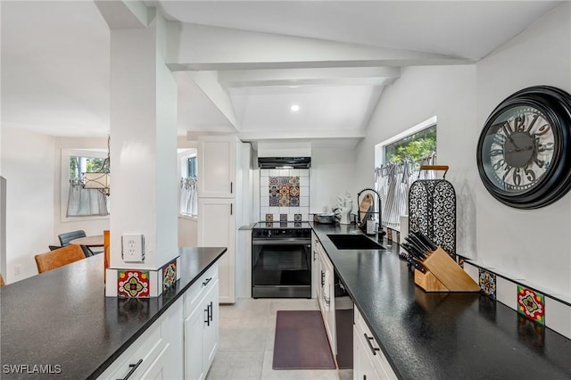 kitchen featuring a healthy amount of sunlight, range with electric stovetop, dark countertops, a sink, and white cabinets