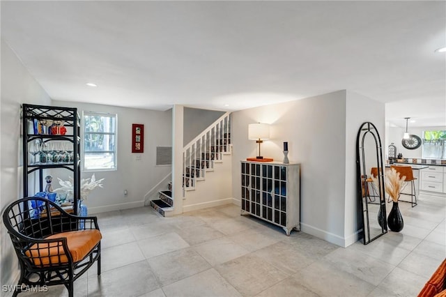 living area with stairs, baseboards, and plenty of natural light