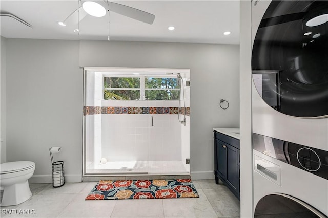 washroom with laundry area, a ceiling fan, baseboards, and stacked washer / dryer