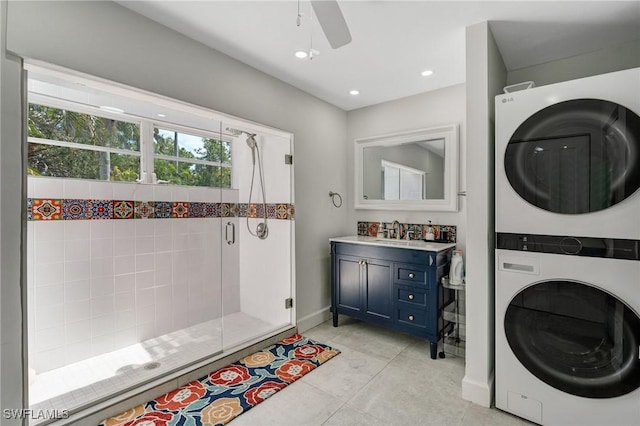 full bathroom featuring a ceiling fan, a stall shower, vanity, baseboards, and stacked washer and clothes dryer