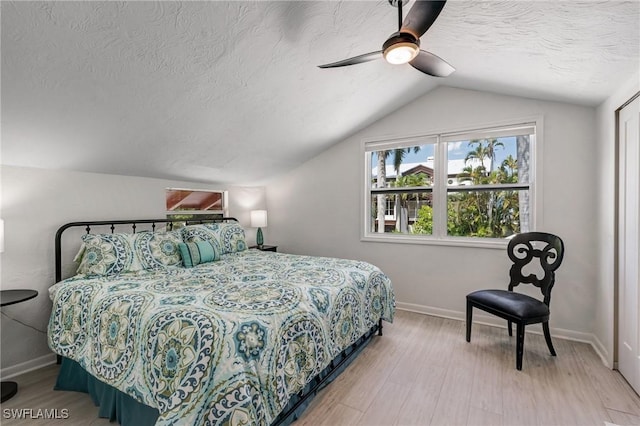 bedroom featuring wood finished floors, baseboards, ceiling fan, a textured ceiling, and vaulted ceiling