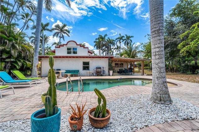 rear view of property with a patio, an outdoor pool, and stucco siding