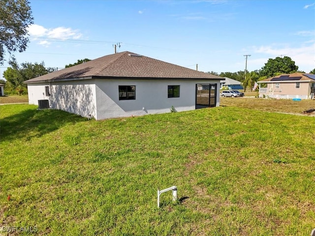 2609 59th St W, Lehigh Acres, FL 33971 - rear view of house featuring a yard, stucco siding, and central AC
