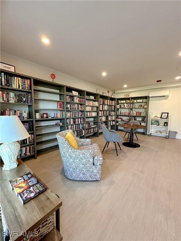 living area with recessed lighting, bookshelves, and a wall unit AC