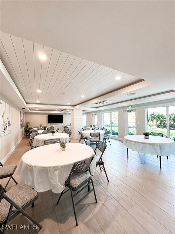 dining area featuring baseboards, a raised ceiling, light wood-style flooring, and recessed lighting