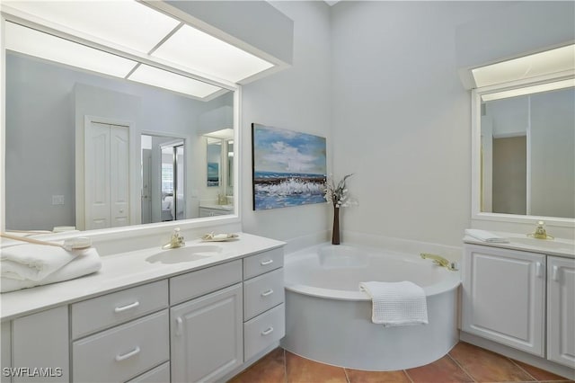 full bath with two vanities, a garden tub, tile patterned floors, and a sink