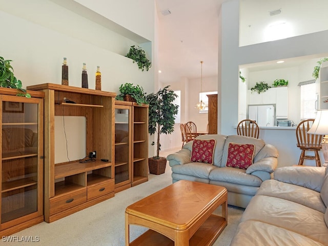 1036 Egrets Walk Cir Unit 202, Naples, FL 34108 - living area featuring an inviting chandelier, a high ceiling, and carpet